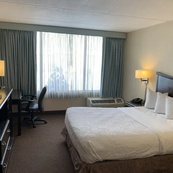 Guestroom with a bed, desk and window at Albany Airport Inn